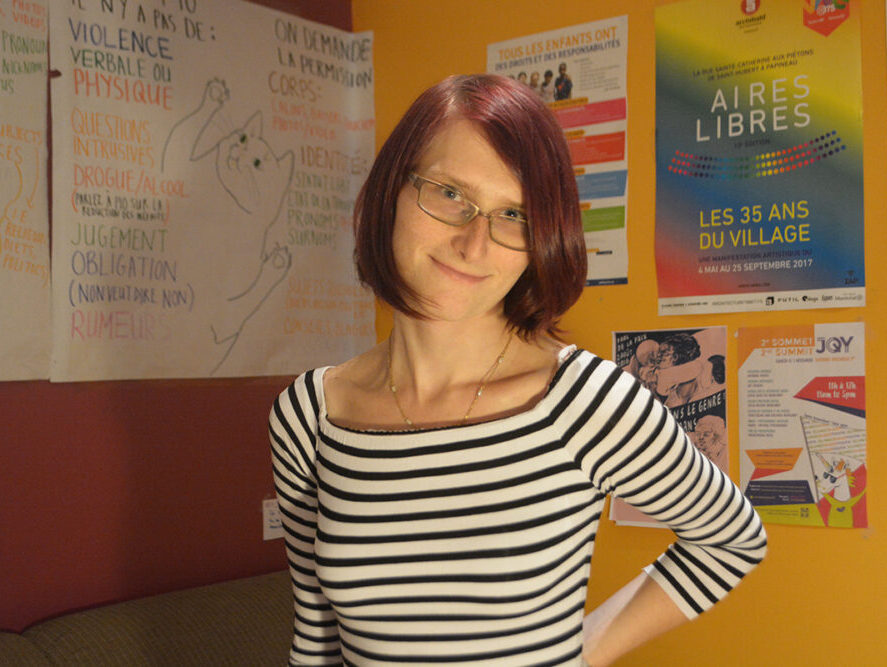 portrait of lizzie who has red short hair, glasses and wears a black and white stripped shirt
