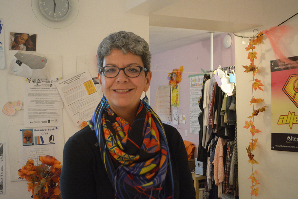 Tealey's mom poses smiling with grey hair, glasses, earrings and a coloured scarf